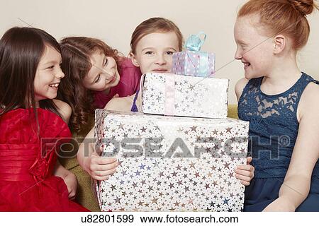 Stock Photo - Girl holding birthday present with friends. Fotosearch