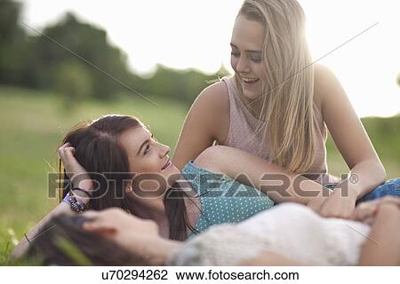 Stock Image - Girls chatting on grass. Fotosearch