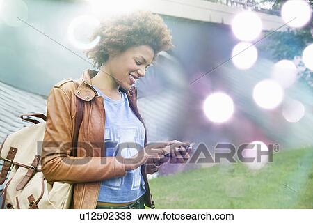 Glowing lights and young woman using smartphone View Large Photo Image Stock Photo - Glowing lights and young woman using smartphone. Fotosearch