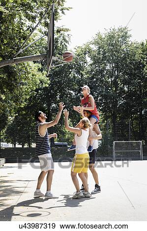 Stock Photo - Group of friends having fun playing basketball. Fotosearch