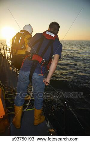 Stock Image - Lifeboat crew looking down at sea from lifeboat. Fotosearch