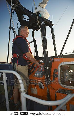 Lifeboat crew steering boat at sea View Large Photo Image Stock Photo - Lifeboat crew steering boat at sea. Fotosearch