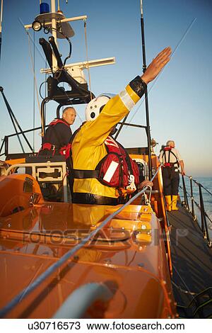 Stock Image - Lifeboat crew training on lifeboat. Fotosearch