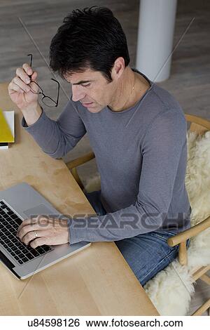 Mature businessman working an laptop at home View Large Photo Image Stock Photograph - Mature businessman working an laptop at home. Fotosearch