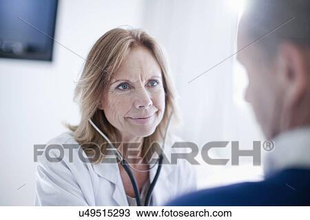 Mature female doctor listening to patients chest View Large Photo Image Stock Image - Mature female doctor listening to patients chest. Fotosearch