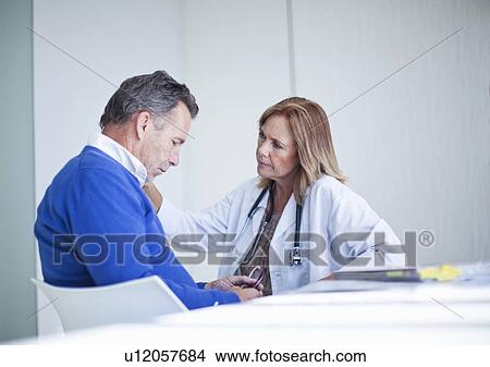 Mature female doctor sympathizing with patient View Large Photo Image Picture - Mature female doctor sympathizing with patient. Fotosearch