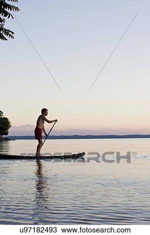 Stock Image - Mature man punting on Lake Starnberg, Bavaria, Germany. Fotosearch
