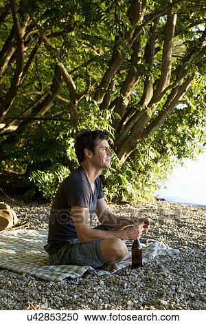 Stock Image - Mature man relaxing on lakeside. Fotosearch