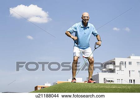 Picture - Mature man stretching with exercise rope in park. Fotosearch