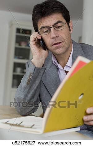 Mature man working at home using mobile phone View Large Photo Image Stock Photo - Mature man working at home using mobile phone. Fotosearch