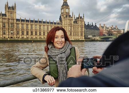 Stock Photo - Mature tourist couple photographing Houses of Parliament, London, UK. Fotosearch