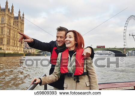 Stock Image - Mature tourist couple sightseeing on Thames boat, London, UK. Fotosearch