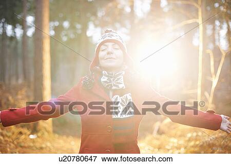 Stock Photo - Mature woman in hat and coat with arms out. Fotosearch