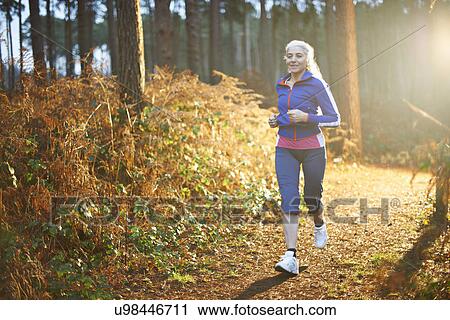 Mature woman jogging on forest path View Large Photo Image Stock Image - Mature woman jogging on forest path. Fotosearch