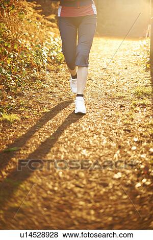 Mature woman jogging on path in sunlight, low section View Large Photo Image Stock Photo - Mature woman jogging on path in sunlight, low section. Fotosearch