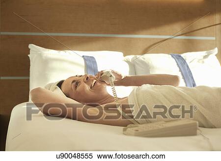 Mature woman lying on bed talking on landline View Large Photo Image Stock Photography - Mature woman lying on bed talking on landline. Fotosearch