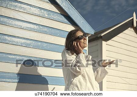 Picture - Mature woman on vacation talking on cellphone, Southwold, Suffolk, UK. Fotosearch