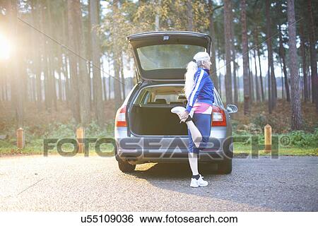 Mature woman stretching leg by car View Large Photo Image Stock Photograph - Mature woman stretching leg by car. Fotosearch