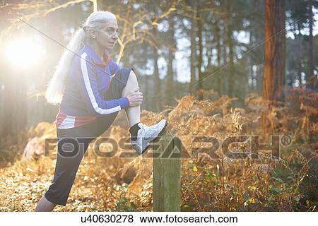 Mature woman stretching leg on wooden post View Large Photo Image Stock Photo - Mature woman stretching leg on wooden post. Fotosearch