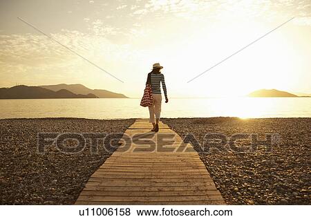 Stock Photo - Mature woman strolling on boardwalk, Fethiye, Turkey. Fotosearch