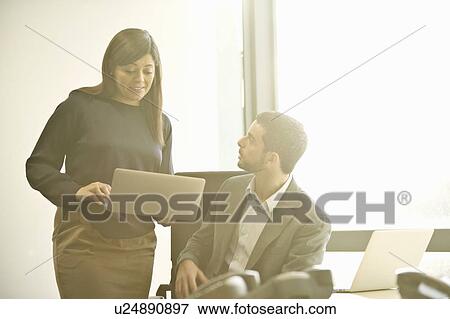 Mid adult business colleagues discussing ideas in office View Large Photo Image Stock Photo - Mid adult business colleagues discussing ideas in office. Fotosearch
