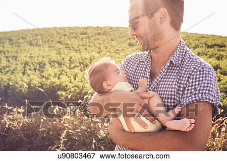 Stock Photo - Mid adult man holding baby daughter. Fotosearch