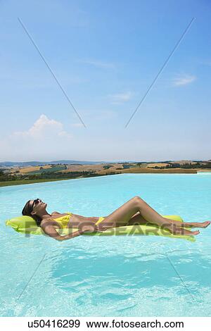 Mid adult woman lying on inflatable mattress in swimming pool View Large Photo Image Stock Photo - Mid adult woman lying on inflatable mattress in swimming pool. Fotosearch