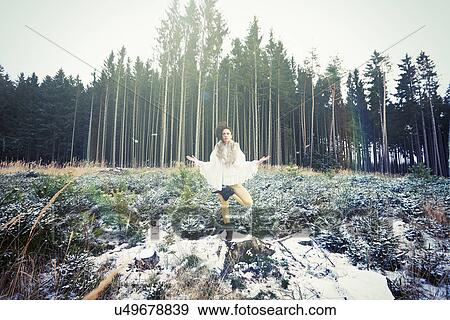 Stock Photo - Mid adult woman practicing standing tree yoga pose in forest. Fotosearch