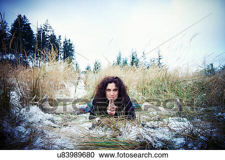 Stock Image - Mid adult woman practicing the splits in forest. Fotosearch