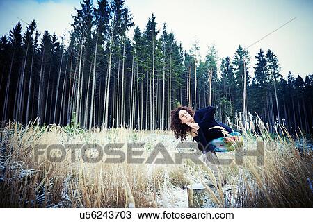 Stock Image - Mid adult woman practicing yoga moves in forest. Fotosearch