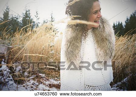 Stock Image - Mid adult woman wearing fur collar in forest. Fotosearch