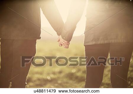 Stock Photo - Mid section of couple, holding hands. Fotosearch