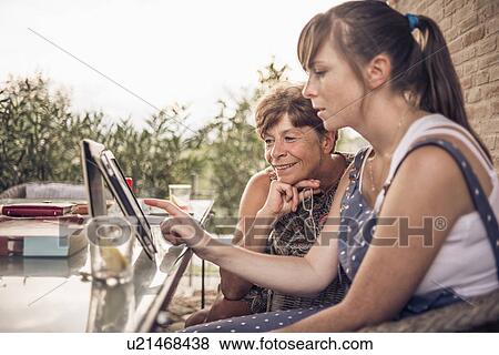 Mother and mid adult daughter looking at digital tablet View Large Photo Image Stock Photo - Mother and mid adult daughter looking at digital tablet. Fotosearch