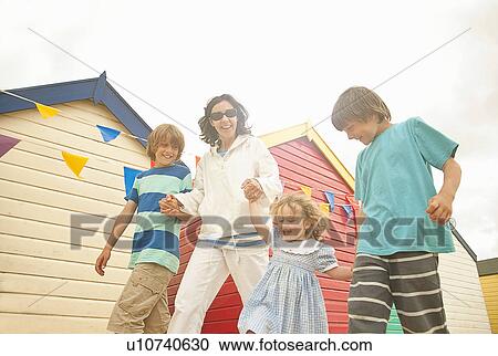 Stock Image - Mother and three children holding hands at coast, Southwold, Suffolk, UK. Fotosearch