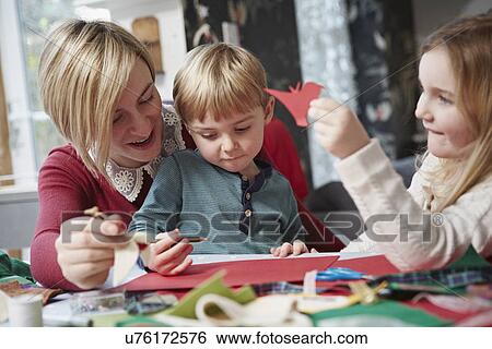 Stock Photograph - Mother and two children drawing at kitchen table. Fotosearch
