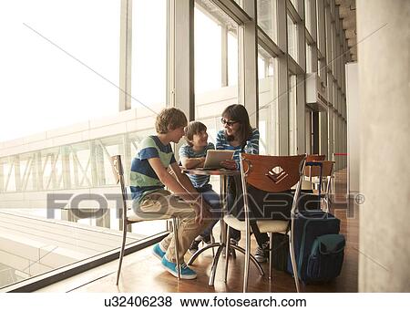 Mother and two sons waiting in departure lounge at airport View Large Photo Image Stock Photo - Mother and two sons waiting in departure lounge at airport. Fotosearch