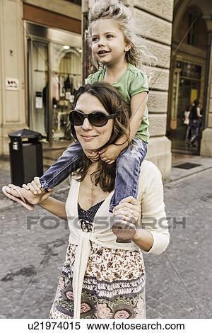 Stock Photography - Mother carrying daughter on shoulders. Fotosearch