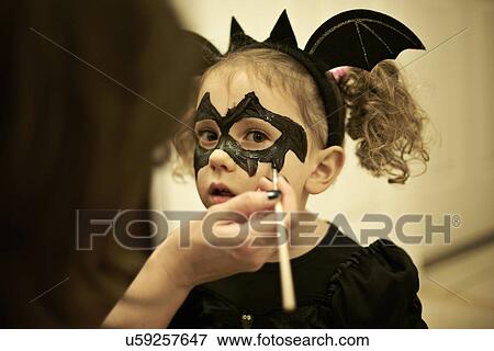 Mother painting daughters face for halloween bat costume View Large Photo Image Stock Photo - Mother painting daughters face for halloween bat costume. Fotosearch