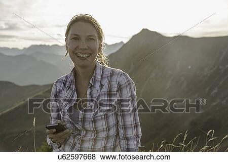 Portrait of a mid adult woman backpacker with cellphone, Achensee, Tyrol, Austria View Large Photo Image Stock Photo - Portrait of a mid adult woman backpacker with cellphone, Achensee, Tyrol, Austria. Fotosearch