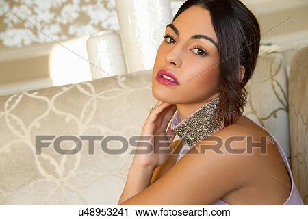 Stock Image - Portrait of attractive young woman on sofa. Fotosearch
