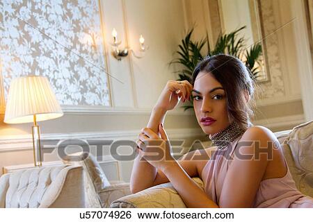 Stock Photograph - Portrait of attractive young woman reclining on sofa. Fotosearch