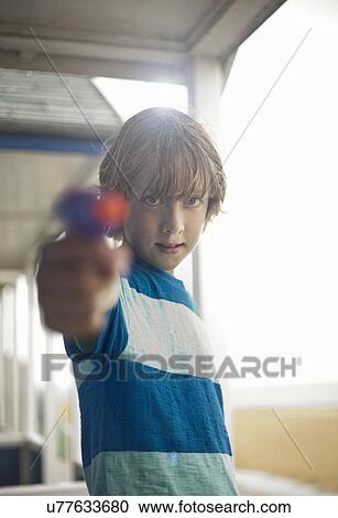 Portrait of boy holding water pistol, Southwold, Suffolk, UK View Large Photo Image Stock Image - Portrait of boy holding water pistol, Southwold, Suffolk, UK. Fotosearch