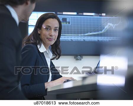 Stock Image - Portrait of businesswoman in meeting in front of screen in office. Fotosearch