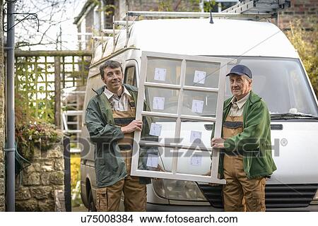 Picture - Portrait of father and son builders holding new window. Fotosearch