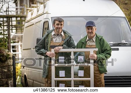 Stock Photography - Portrait of father and son builders holding new window for installation. Fotosearch