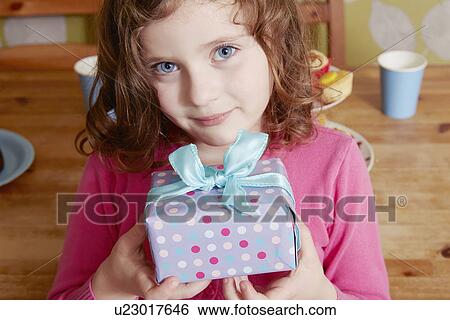 Stock Photograph - Portrait of girl holding birthday present. Fotosearch