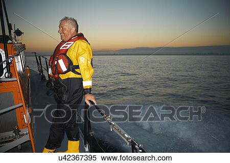 Stock Photography - Portrait of mature man holding lifeboat railing at sea. Fotosearch