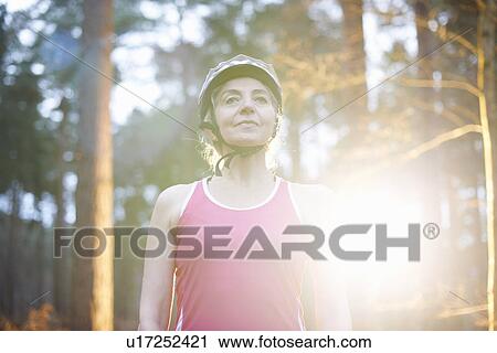 Stock Image - Portrait of mature woman wearing bicycle helmet. Fotosearch