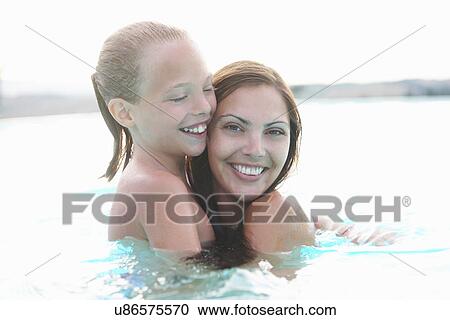 Stock Image - Portrait of mother and daughter in outdoor swimming pool. Fotosearch