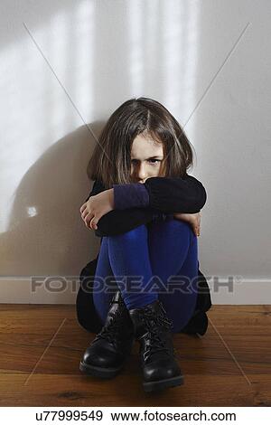 Portrait of stubborn young girl sitting on floor hugging knees View Large Photo Image Stock Photo - Portrait of stubborn young girl sitting on floor hugging knees. Fotosearch